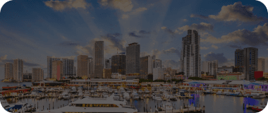 Aerial view of Miami's skyline at sunset with vibrant skies and yachts in the marina