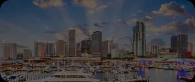 Aerial view of Miami's skyline at sunset with vibrant skies and yachts in the marina