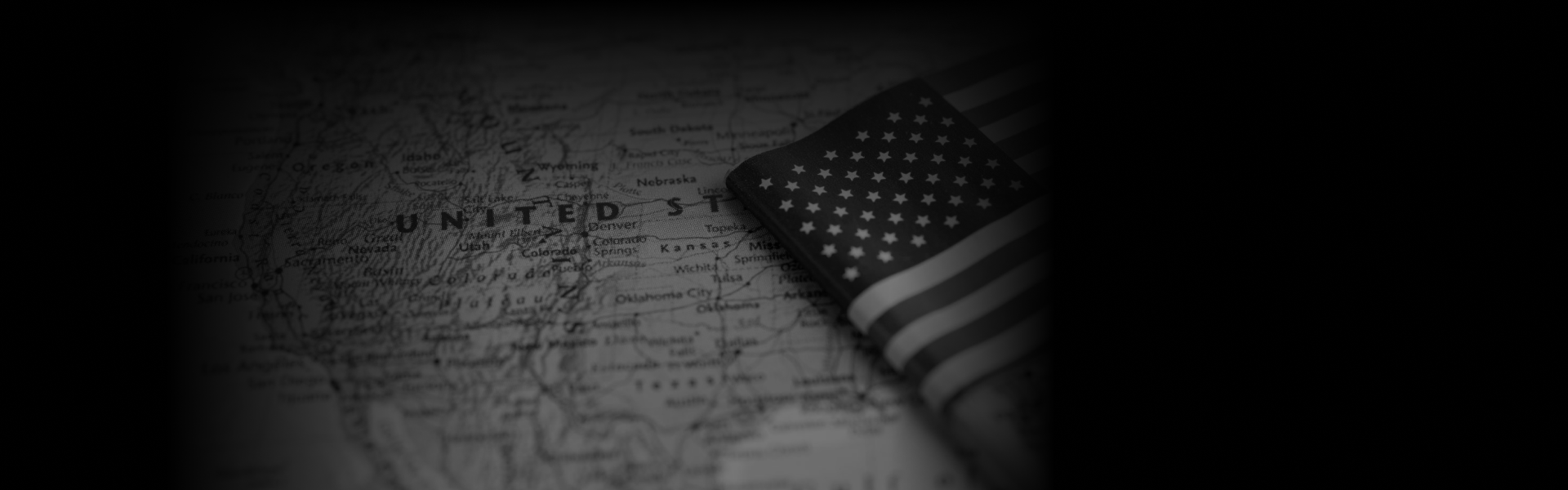 A grayscale map of the United States with a folded American flag placed over the Midwest, accompanied by the text "Premium Transportation Services Across All States" in bold white letters at the bottom.